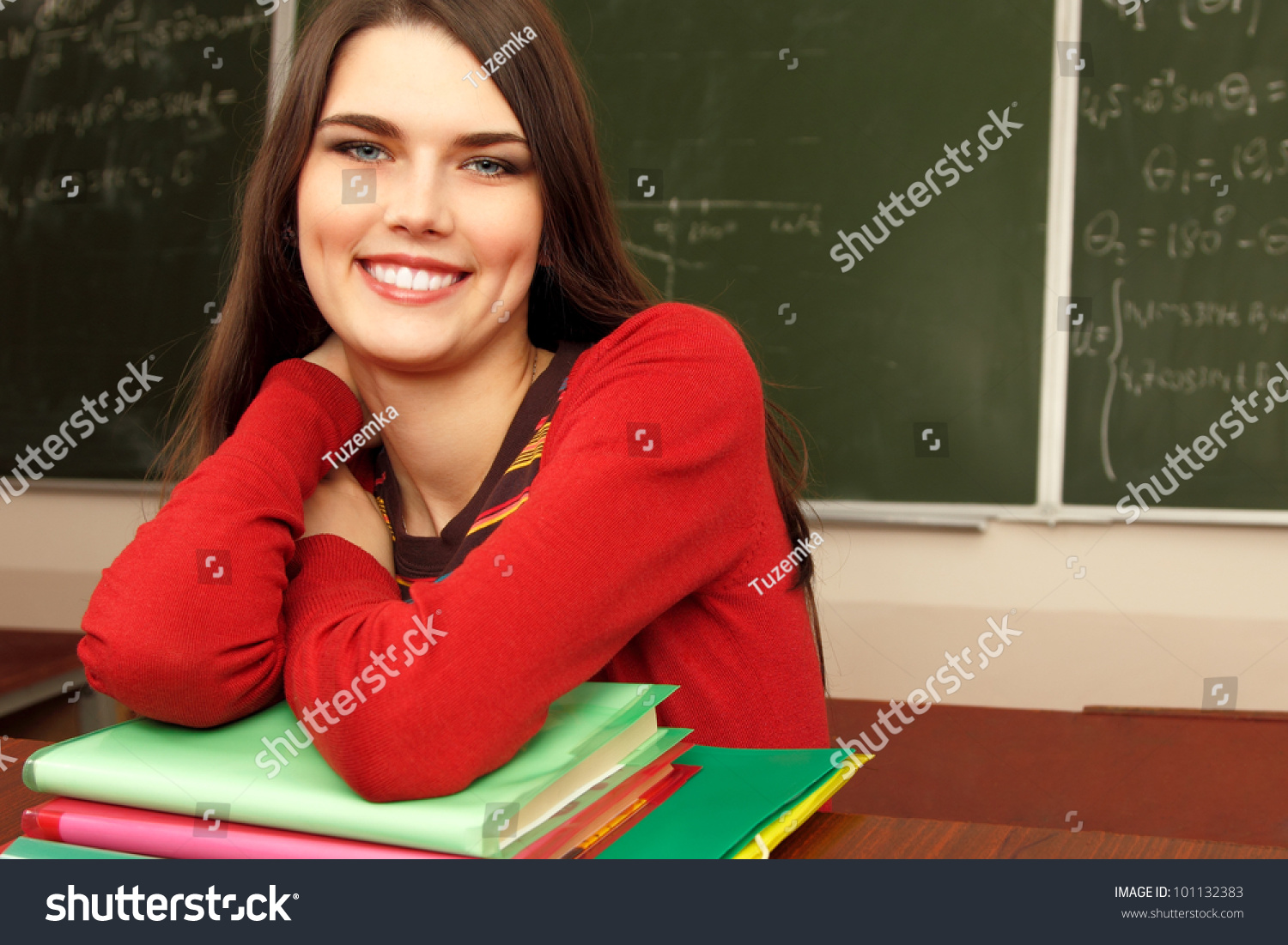 beautiful teen girl high achiever in classroom near desk happy