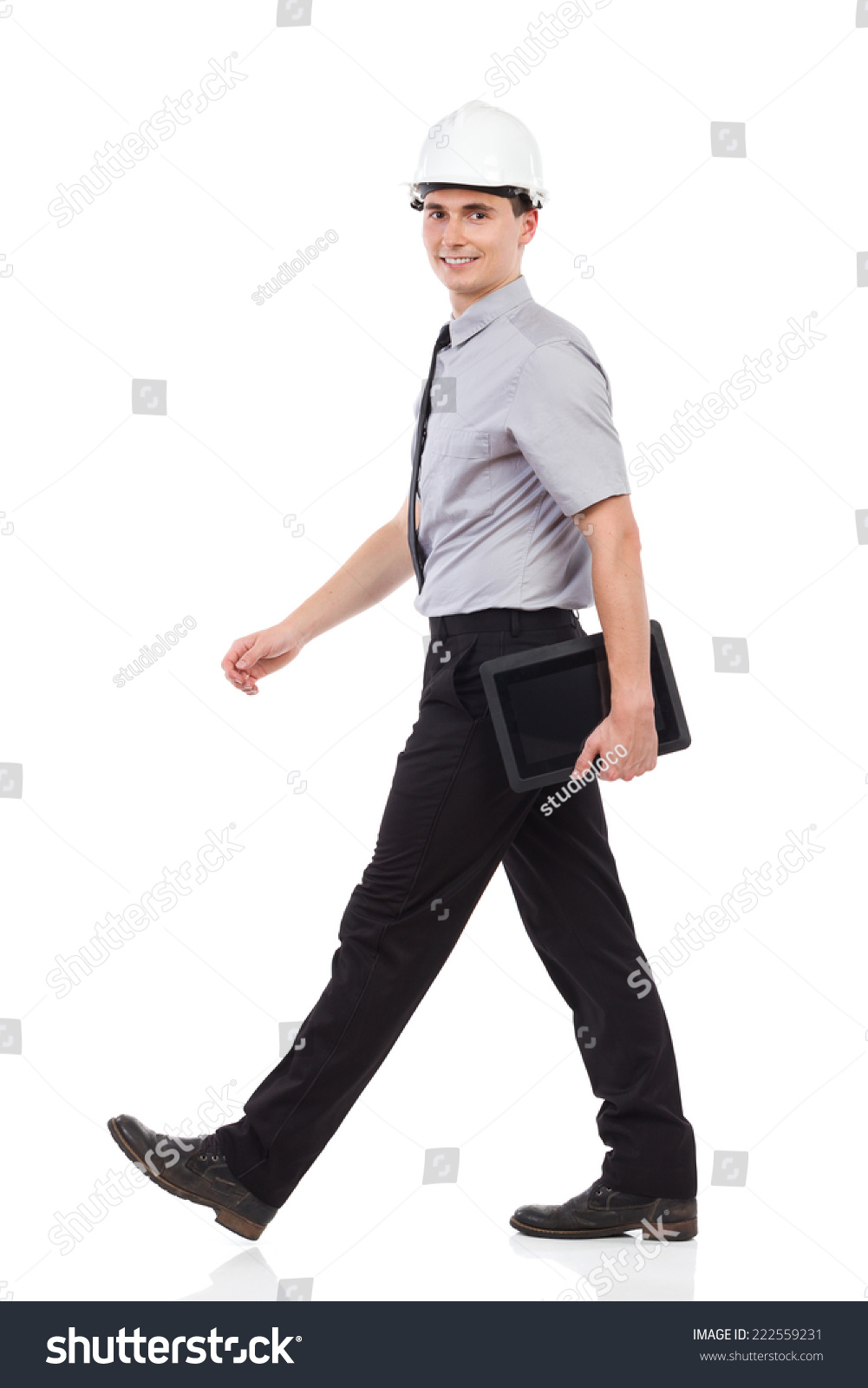 工程师用数码平板行走,侧面,看着相机.全长影棚拍摄孤立在白色的.