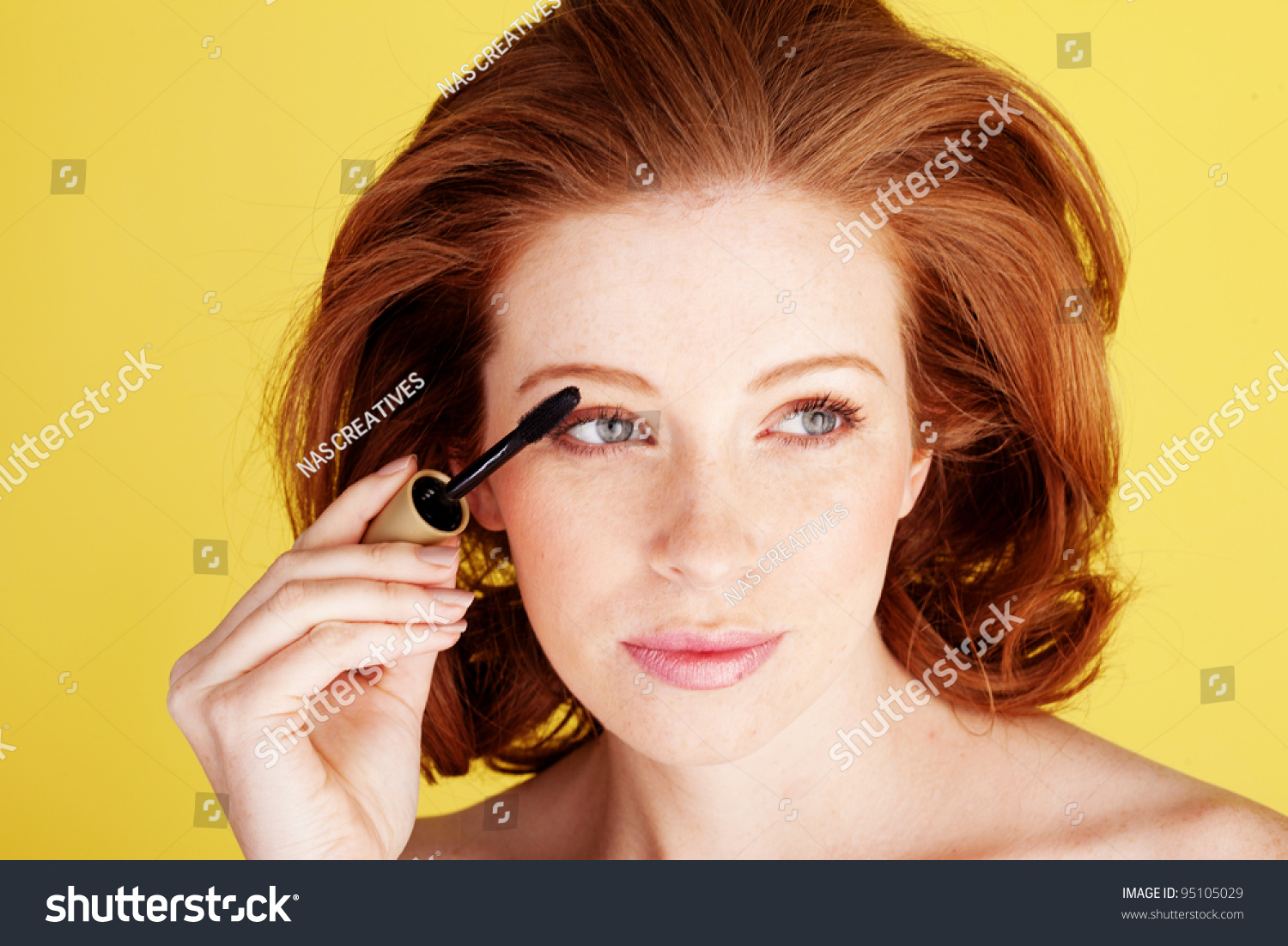 迷人的红头发女人使用刷涂睫毛膏睫毛